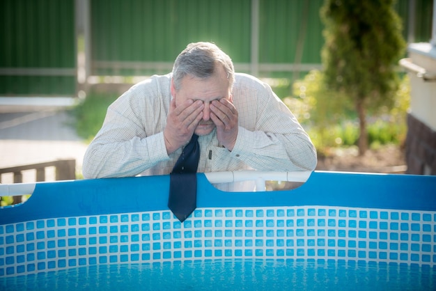 A handsome man in a business suit washes his face by the pool Summer heat