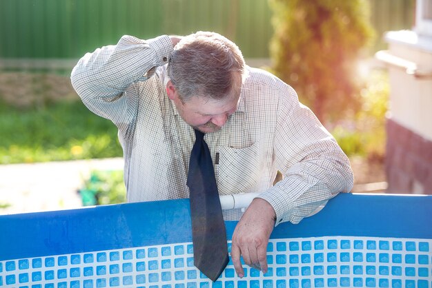 A handsome man in a business suit washes his face by the pool Summer heat