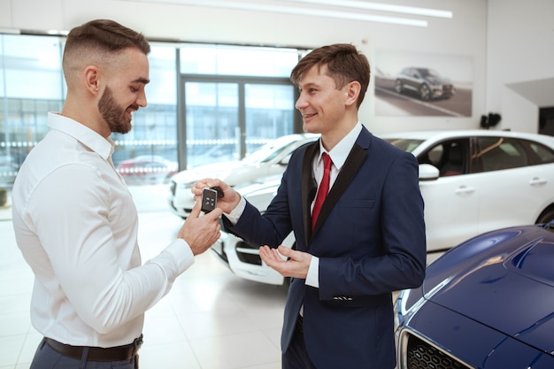 ハンサムな男がディーラーで新しい車を買う