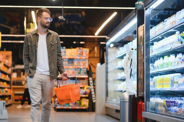 현대 슈퍼마켓이나 식료품 가게에서 건강한 음식과 음료를 구입하는 잘생긴 남자 생활 방식과 소비주의 개념