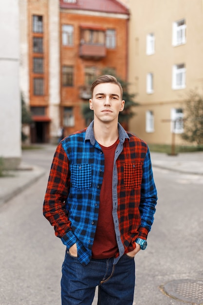 Handsome man in a checkered shirt on the of buildings