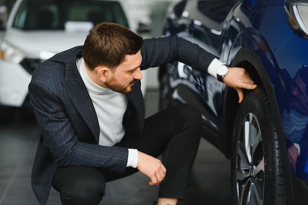 Handsome man choosing a car in a show room