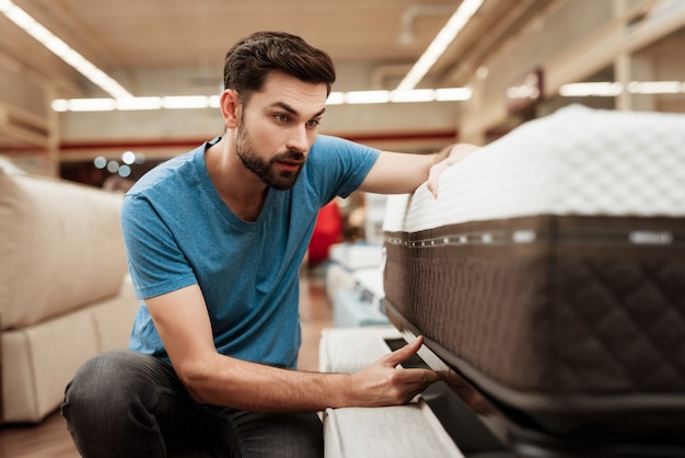 Handsome Man Choosing Mattress in Furniture Store