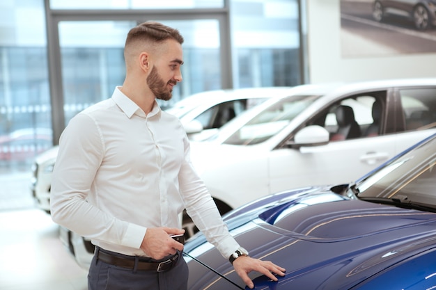 Uomo bello che sceglie nuova automobile al concessionario