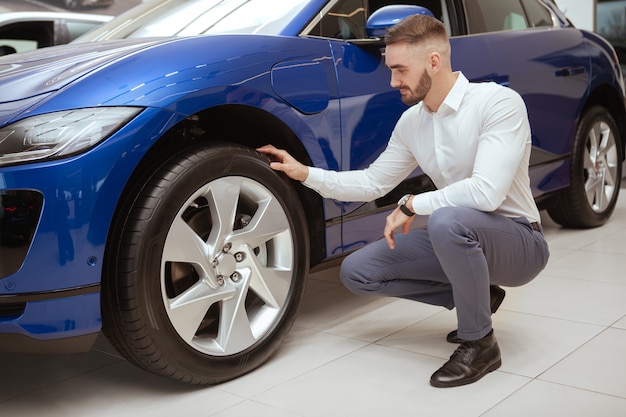 Handsome man choosing new automobile at the dealership