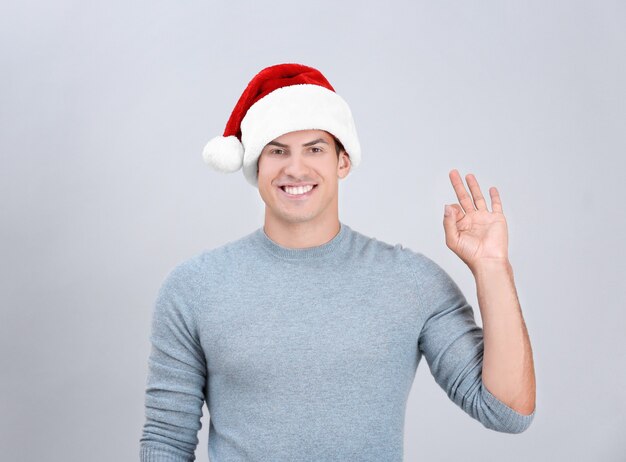 Handsome man in Christmas hat on light background