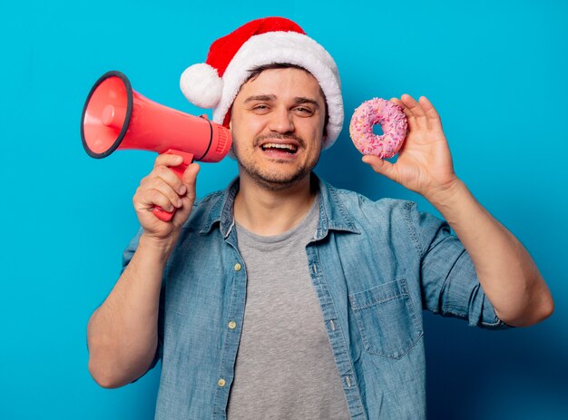 Handsome man in Christmas hat with donut and loud-hailer