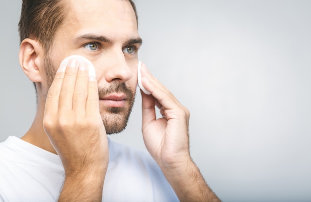 Handsome man cleansing his skin with cotton pads