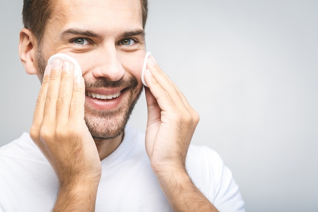 Handsome man cleansing his skin with cotton pads