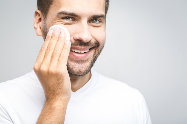 Handsome man cleansing his skin with cotton pads