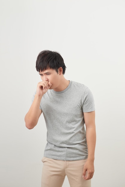 Handsome man coughing into his fist isolated on a white background