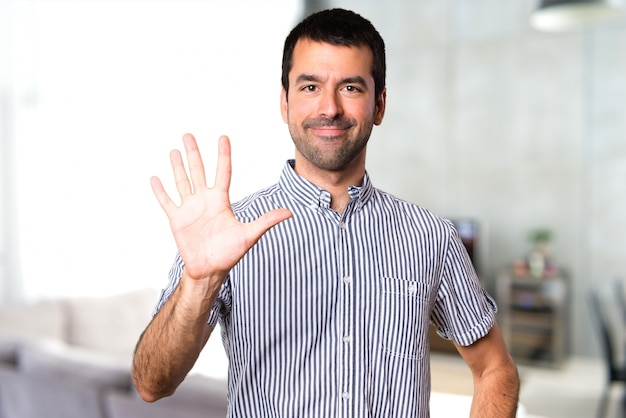 Handsome man counting five inside house