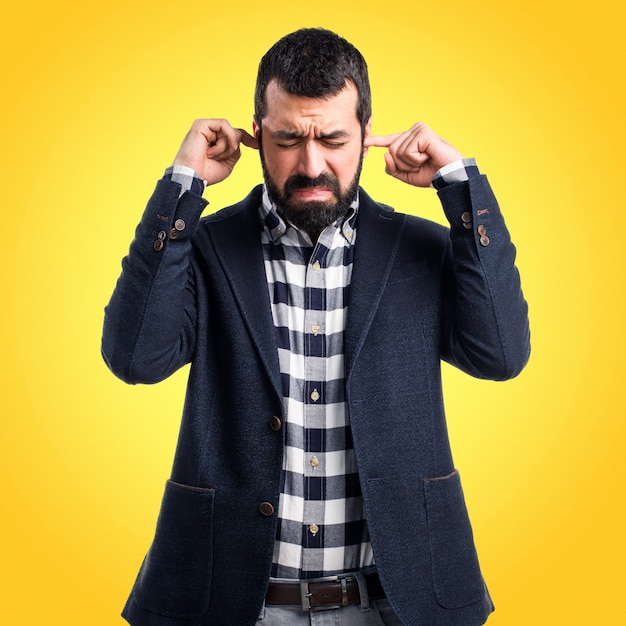 Handsome man covering his ears on colorful background