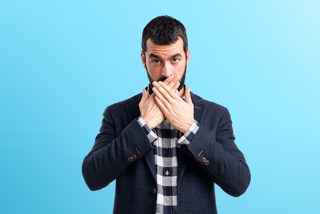 Handsome man covering his mouth on colorful background