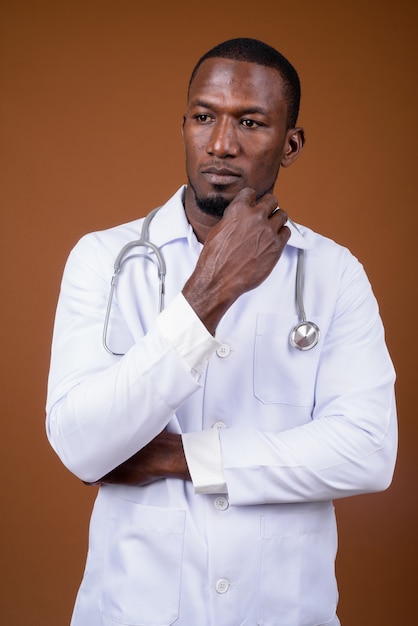 Handsome man doctor against brown