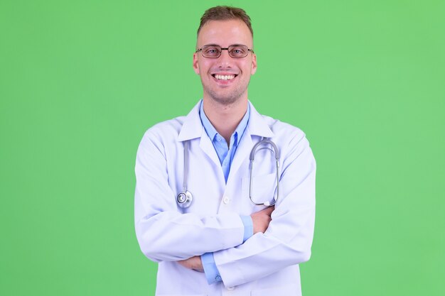 handsome man doctor wearing eyeglasses against green wall