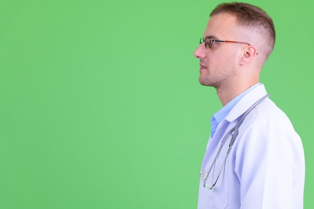 handsome man doctor wearing eyeglasses against green wall