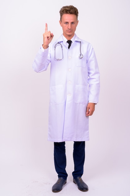 handsome man doctor with blond curly hair against white wall