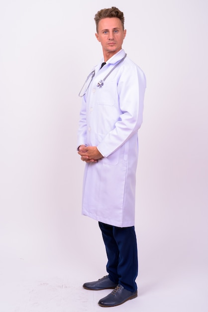 handsome man doctor with blond curly hair against white wall