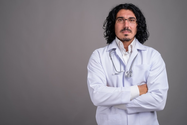 Handsome man doctor with mustache against gray wall