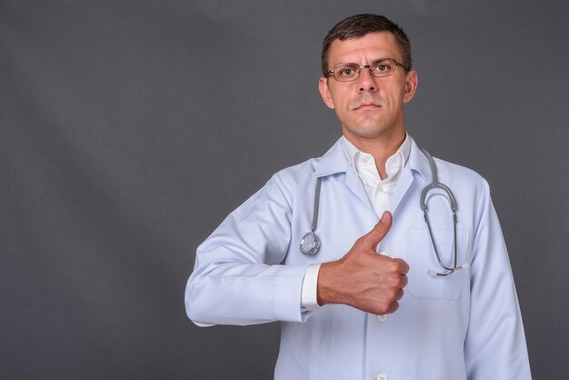 Medico uomo bello con i capelli corti su sfondo grigio