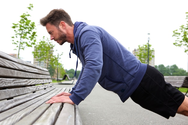 Foto bell'uomo facendo pushup sulla panchina