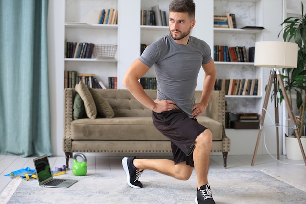 Handsome man doing sport exercise at home during quarantine. Concept of healthy life