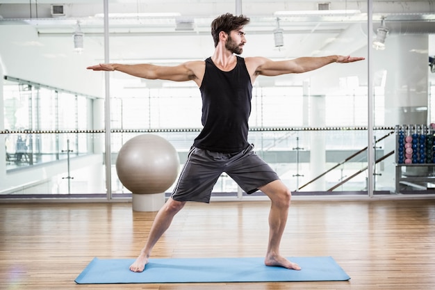 Handsome man doing yoga on mat in the studio