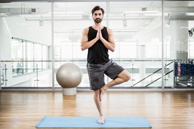 Uomo bello che fa yoga sulla stuoia in studio