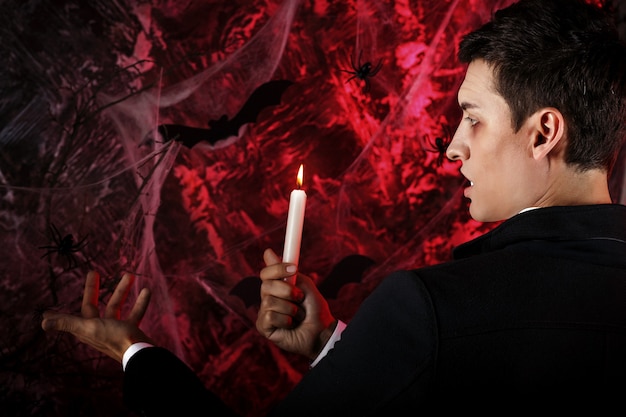 Handsome man dressed in a Dracula costume for Halloween. attractive vampire with candles