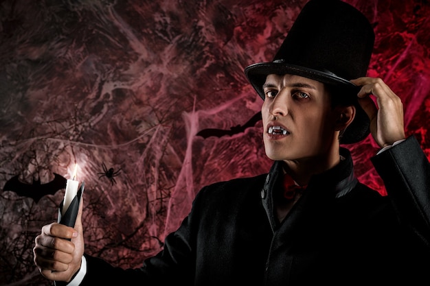 Handsome man dressed in a Dracula costume for Halloween.  horrific vampire with candles