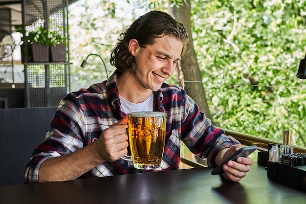 Handsome man drinking beer on summer terrace cafe.