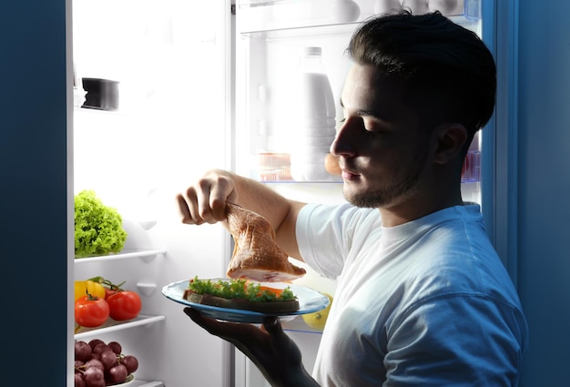 Handsome man eating chicken in kitchen Unhealthy food concept