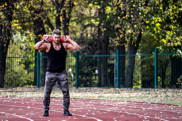 Handsome man exercising outdoors Muscular sportsman training in green wide park