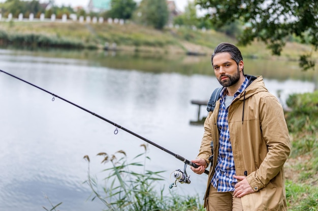 Handsome man fishing with rod on lake