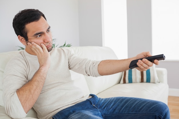 Handsome man getting bored of tv programs 