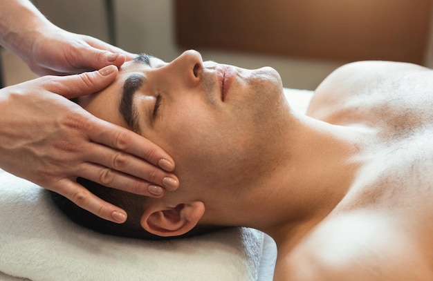 Handsome man getting professional face massage in spa salon