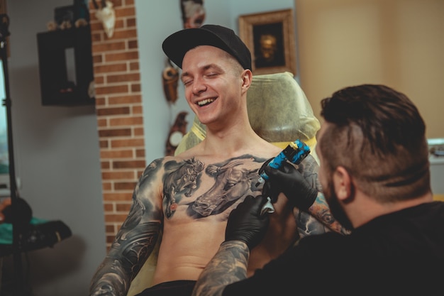 Uomo bello che ottiene un tatuaggio allo studio di arte alternativa