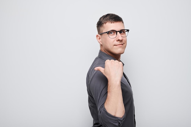 Photo handsome man in glasses pointing aside finger demonstrating empty space for product or text isolated on white studio background