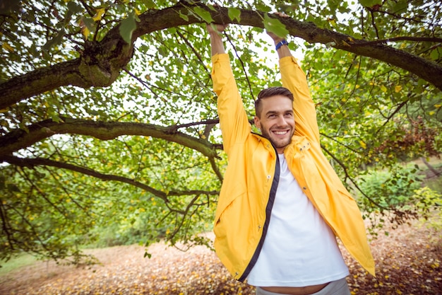 Handsome man hanging from tree