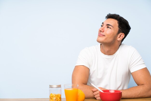 Bell'uomo a fare colazione ridendo e alzando lo sguardo