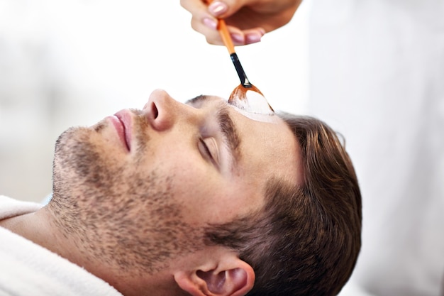 handsome man having facial in spa salon