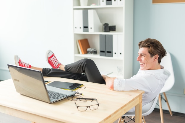 Handsome man having fun sitting at the table with foot on it