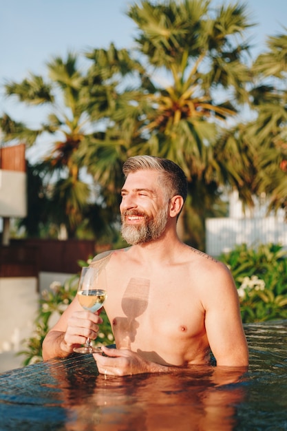 Handsome man having a glass of wine in the pool