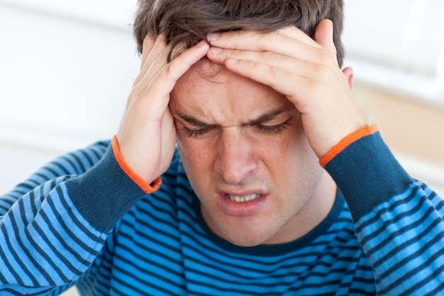 Handsome man having a headache in the living-room