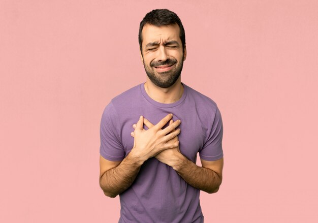 Handsome man having a pain in the heart on isolated pink background