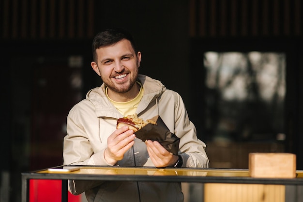 Handsome man having traditional hot dog cuisine during rest break caucasian guy enjoying street