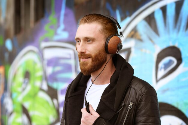 Handsome man in headphones listening to music outdoors