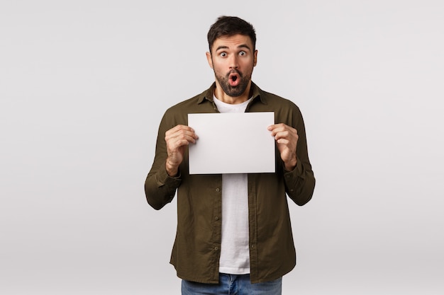 Handsome man holding blank paper sheet or document