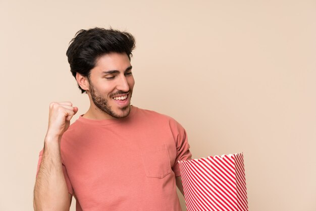 Uomo bello che tiene una ciotola di popcorn